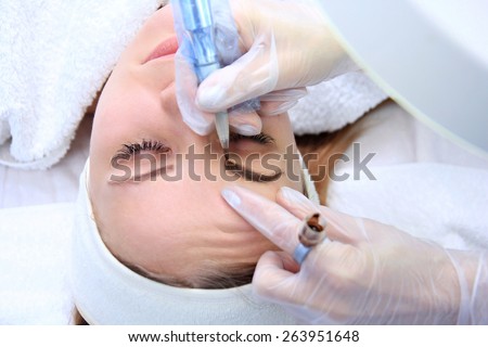 Cosmetologist applying permanent make up on eyebrows- eyebrow tattoo
