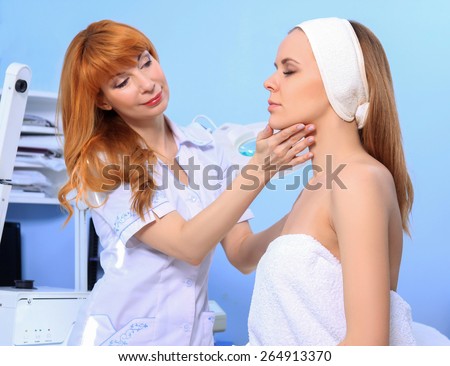 Woman doctor cosmetologist examines the skin of a young girl. Preparing for the beauty treatment.