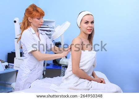 Doctor inspecting woman patient skin on her for melanoma