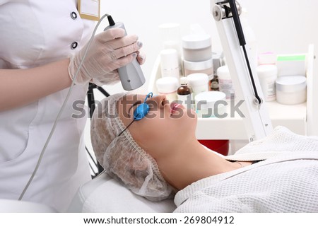 Cosmetician in safety glasses using laser for facial treatment in cosmetology clinic
