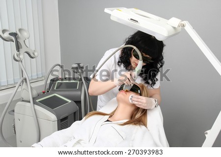 Laser hair removal in the beauty salon. Woman having facial hair removal. Laser hair removal equipment in the background.