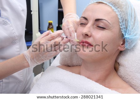 Mesotherapy. Adult woman receiving anti-aging procedure in the beauty salon. Doctor beautician making injections in the lips.