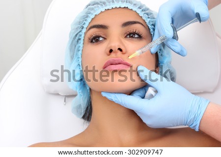 Beautiful girl on rejuvenation procedure in beauty clinic filler injection. Injection in her lips.