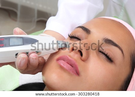 Woman receiving cleansing therapy with a professional ultrasonic equipment in cosmetology office