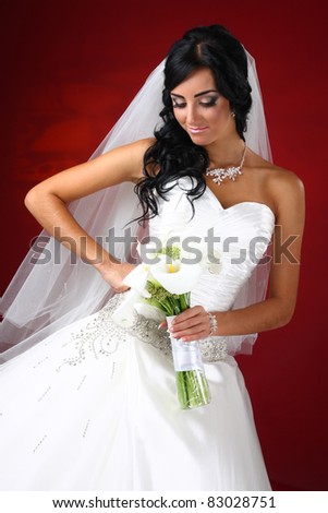 The beautiful bride with a bouquet made of callas on a red background