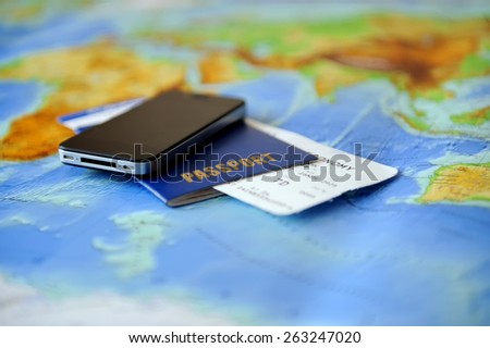 Passport, ticket, phone on a background map of the world. Traveling concept