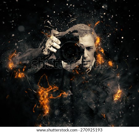 Professional photographer with dslr camera in fire on dark background
