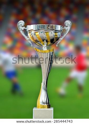Golden trophy in grass on soccer field background