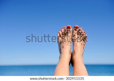 Women\'s beautiful legs on the beach near sea