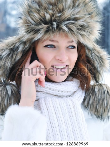 Beautiful young woman with mobile phone in winter