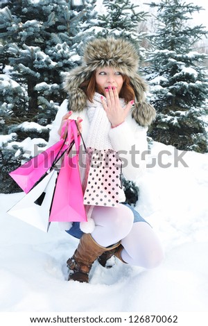 Beautiful happy girl with shopping bags in a winter park