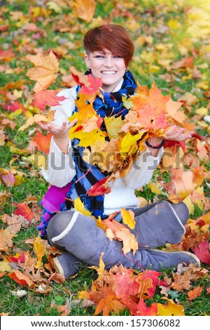 Young girl in an autumn park throws leaves