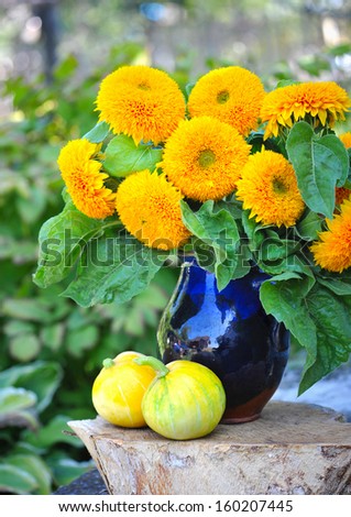 Bouquet of sunflowers are with the decorative pumpkins on a natural background