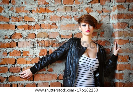Beautiful young woman standing near brick wall