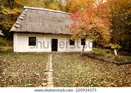 Old hut with a straw roof in autumn forest. Ukrainian Museum of Life and Architecture
