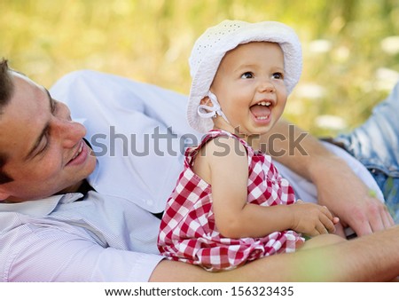 Happy young father spending time outdoor on a summer day with his beautiful daughter