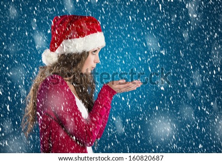Beautiful woman with christmas hat on blue winter background with snowflakes