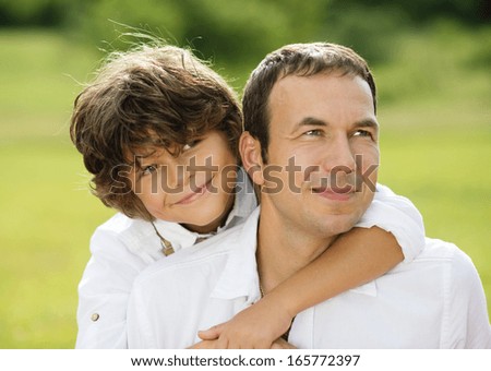 Father and son hugging and playing together in green nature