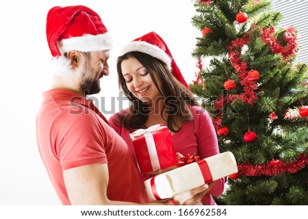Young couple is dancing close to christmas tree. Woman is pregnant.