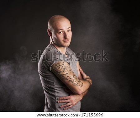 Handsome young man with tattoo, isolated on black.