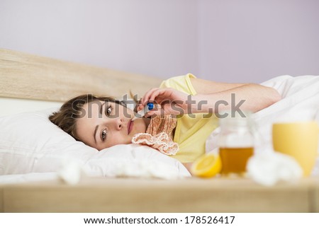 Sick woman lying in bed with high fever. She has cold and flu. In front of her is tea with lemon and honey.
