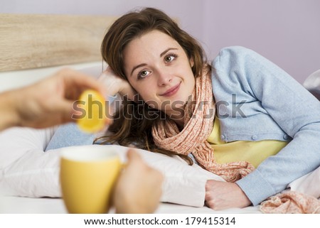 Sick woman lying in bed with high fever. She has cold and flu. In front of her is tea with lemon.