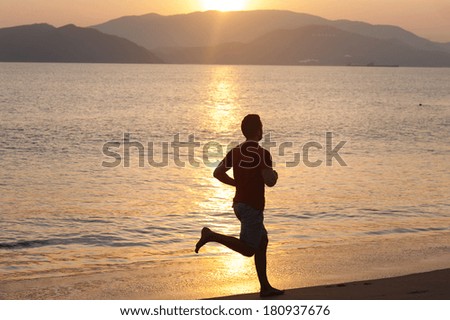 Silhouette of sport active man running and exercising on the beach at sunset.