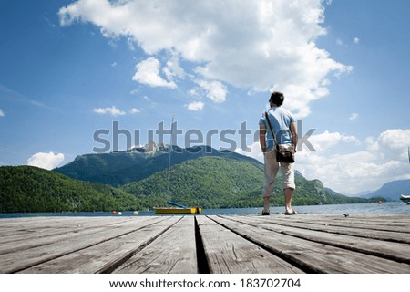 Young man standing on the pier by the lake