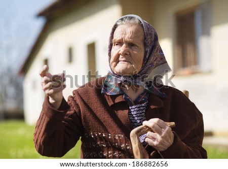 Very old woman with head scarf sitting and relaxing in the garden