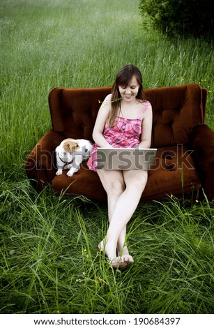 Woman using laptop on couch in sunny field in countryside