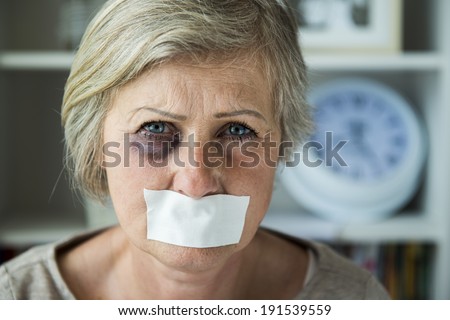 Senior woman with black eye and tape on her mouth, victim of domestic violence