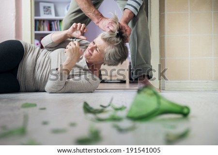 Woman victim of domestic violence and abuse. Mature woman scared of a man with broken bottle