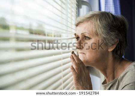 Scared woman is looking through the window. Having bruise on her face