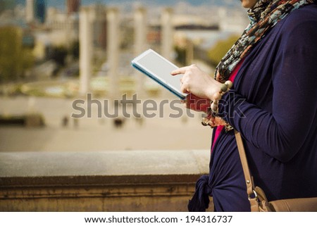 Pretty young female tourist using digital tablet and enjoying the view in Barcelona, Spain.