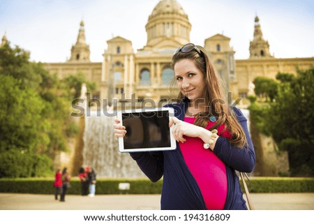 Pretty young female tourist using digital tablet and posing in front of the fountain in Barcelona, Spain.