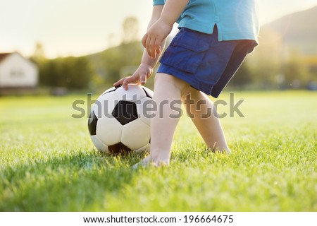 Close-up of little boy playing football on football pitch