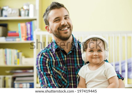 Portrait of happy father and his little daughter listening to music with headphones