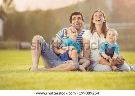 Happy family is relaxing and sitting on football pitch