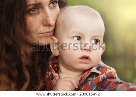 Portrait of a crying little boy who is being held by her mother, outdoors