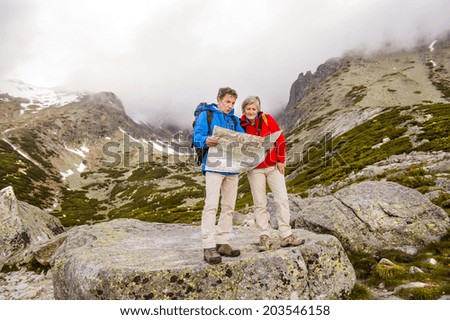 Senior hikers couple looking at the hike map during the hike in beautiful mountains