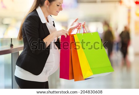Young pregnant woman with shopping bags in shopping mall