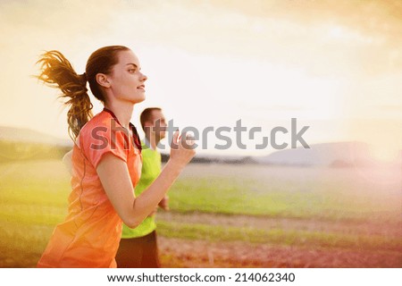 Cross-country trail running people at sunset. Runner couple exercising outside as part of healthy lifestyle.