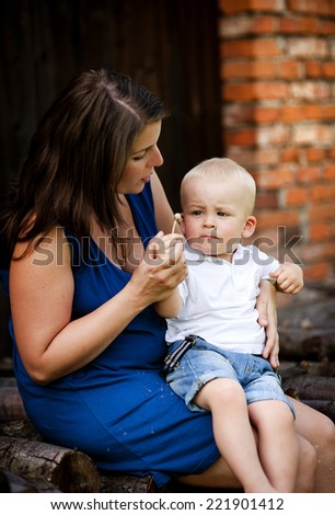 Happy mother with little son spending time in nature by the old house