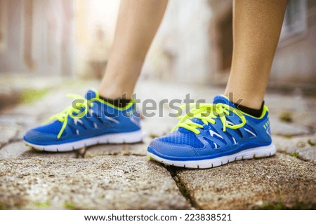 Female runner getting ready for training on tiled pavement in city center, closeup on shoes