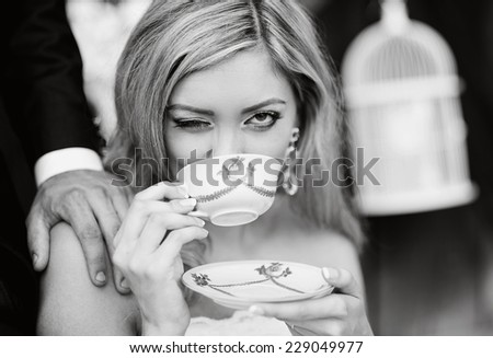 Bride drinking coffee from vintage cup and sitting by the old house