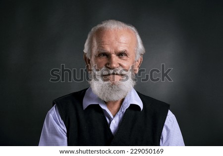 Portrait of old bearded man, posing in studio on black background