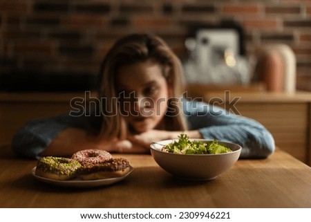 Young woman having diet, deciding between salad and donuts. Foto stock © 