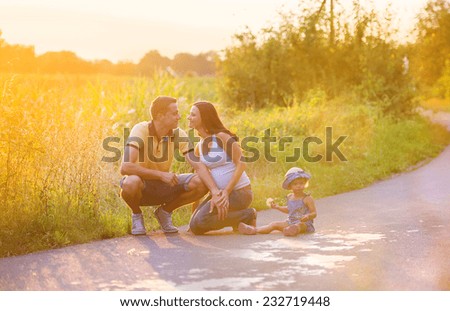 Father pregnant mother and daughter playing outside in nature