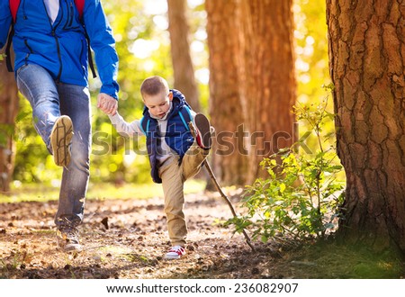 Father and son walking during the hiking activities in autumn forest at sunset