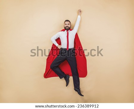 Manager in a superman pose wearing a red cloak. Studio shot on a beige background.